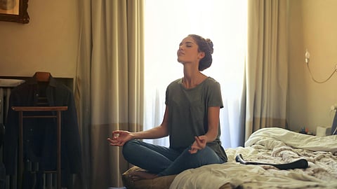 Woman Meditating In Bedroom
