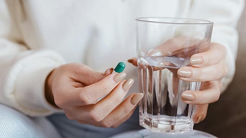 woman holding vitamin capsule and a glass of water