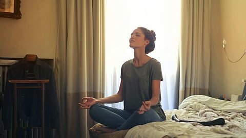 Woman Meditating In Bedroom