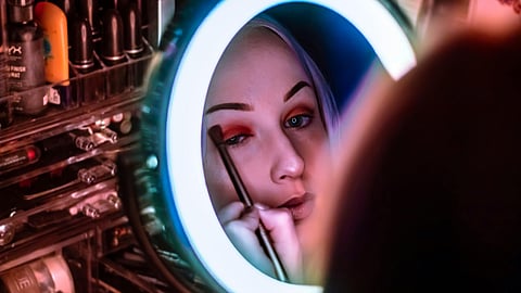 Woman Facing Mirror Applying Eyeshadow