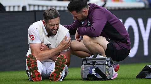 Chris Woakes sits on the ground injured