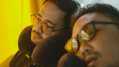 man sleeping wearing neck pillow