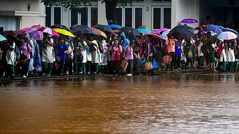 Students walk along a road amid heavy rainfall in the wake of Cyclone Ditwah
