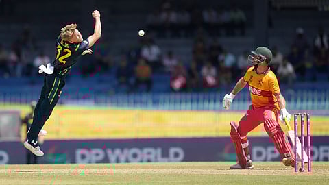 Australia's Nathan Ellis, left, jumps to catch a ball as Zimbabwe's Ryan Burl, right, watch during the T20 World Cup cricket match