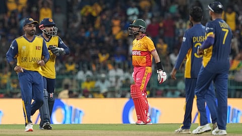 Zimbabwe's captain Sikandar Raza, center, leaves the ground after losing his wicket as Sri Lanka's players celebrate his wicket during the T20 World Cup cricket match