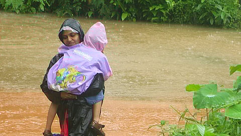കോഴിക്കോട് വെള്ളംപൊങ്ങിയ പ്രദേശത്ത് നിന്നും കുഞ്ഞിനെയും വാരിയെടുത്ത് രക്ഷപ്പെടുന്ന യുവതി/ചിത്രം: എക്സ്പ്രസ്