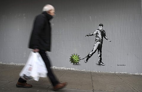 സ്കോട്ലൻഡിലെ ഗ്ലാസ്ഗോയിൽ കോവിഡ് പ്രമേയമാക്കി വരച്ചിരിക്കുന്ന ചുവർചിത്രത്തിനു മുന്നിലൂടെ നടന്നു പോകുന്ന ആൾ