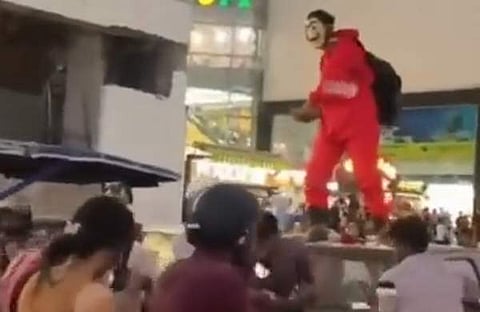 മുഖംമൂടി ധരിച്ച് കാറിന്റെ മുകളിൽ കയറി നോട്ടുകൾ വിതറുന്ന ദൃശ്യം