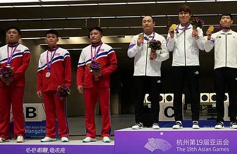 വെള്ളി നേടിയ ഉത്തര കൊറിയ താരങ്ങൾ മെഡൽ പോഡിയത്തിൽ അലക്ഷ്യമായി നിൽക്കുന്നു/ എപി