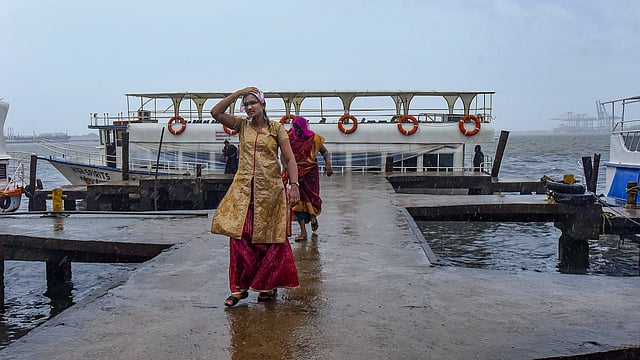 കനത്തമഴയിൽ ഫെറിയിലൂടെ നടന്ന് പോകുന്ന യാത്രക്കാർ