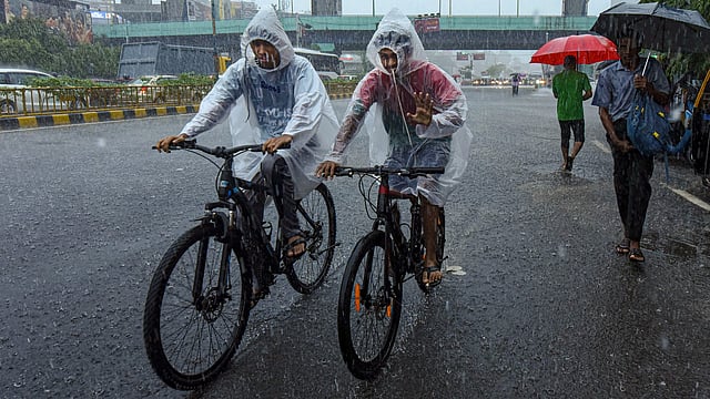 മഴയത്ത് സൈക്കിളിൽ യാത്ര ചെയ്യുന്നവർ