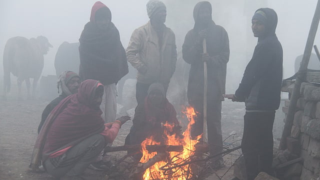 People gather around the bonfire to keep themselves warm on a cold winter morning, in Gurugram