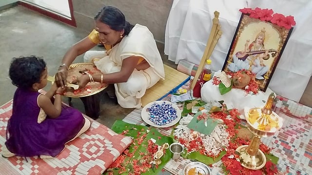 കളരിയിലെ പരമ്പരാഗത അധ്യാപകരായ ‘ആശട്ടി’ കുട്ടിയെ അക്ഷരങ്ങൾ എഴുതിപ്പിക്കുന്നു