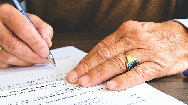 old man signs in a document