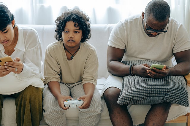 Multiethnic family spending time together on couch with gadget