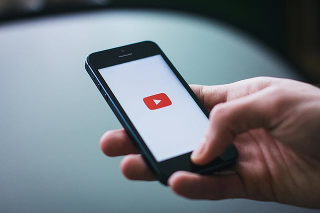 Person Holding a phone with YouTube icon