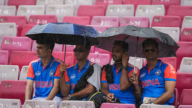 People take cover under umbrellas as it rains before the start of the ICC Women's World Cup 2025 final