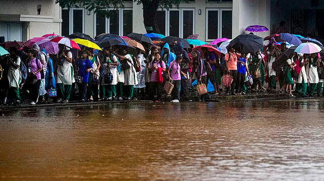 Students walk along a road amid heavy rainfall in the wake of Cyclone Ditwah