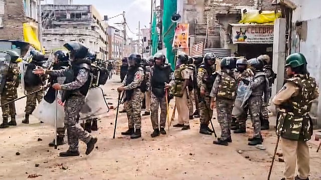 Security personnel stand guard following stone-pelting incidents during protests against the proposed removal of a portion of the 'Shahi Masjid' for road widening