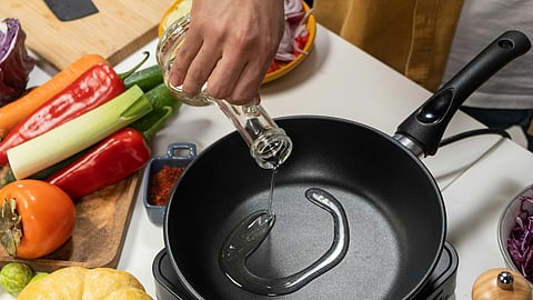 Person Pouring Cooking Oil in Frying Pan