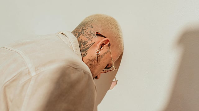 Bald Man Leaning Head Against a White Wall