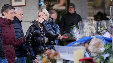 People mourn beside candles and flowers near the Le Constellation bar, where a devastating fire left dead and injured during the New Year's celebrations in  Switzerland
