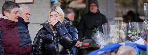 People mourn beside candles and flowers near the Le Constellation bar, where a devastating fire left dead and injured during the New Year's celebrations in  Switzerland
