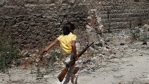kid walking by carrying a machine gun