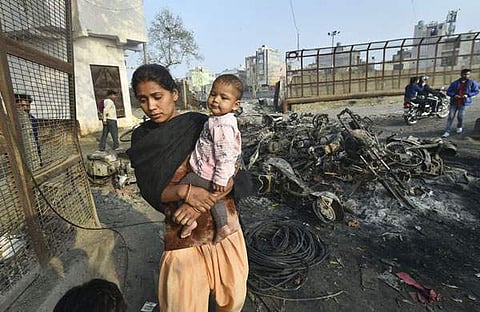 യമുനാ വിഹാറില്‍ ചുട്ടെരിക്കപ്പെട്ട വാഹനങ്ങള്‍ക്കിടയിലൂടെ കുഞ്ഞുമായി നീങ്ങുന്ന യുവതി/പിടിഐ