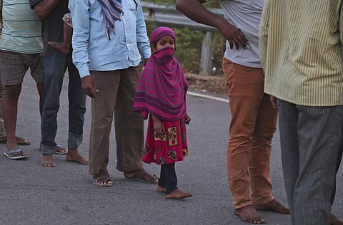 സൗജന്യ ഭക്ഷണത്തിനായി വരി നിൽക്കുന്ന കുടിയേറ്റ തൊഴിലാളികൾക്കിടയിൽ അവരിലൊരാളുടെ മകൾ/ ഫോട്ടോ: എപി