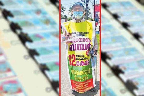 വേഷം ഓണം ബംബറിന്റെ ബാനർ ; ലോട്ടറി ടിക്കറ്റ് വിൽപ്പനയ്ക്ക് വേറിട്ട തന്ത്രവുമായി 68 കാരൻ