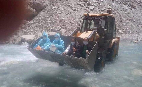 ജെസിബിയില്‍ നദികടക്കുന്ന കോവിഡ് മുന്നണി പോരാളികള്‍