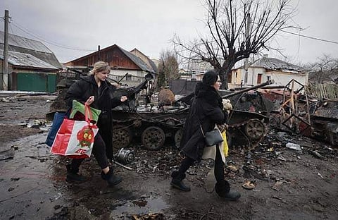 തകര്‍ന്ന റഷ്യന്‍ ടാങ്കുകള്‍ക്കു സമീപത്തുകൂടെ നീങ്ങുന്ന യുക്രൈനികള്‍/എപി