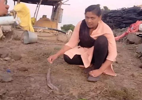 കിണറ്റില്‍ നിന്ന് പിടികൂടിയ പാമ്പുമായി യുവതി