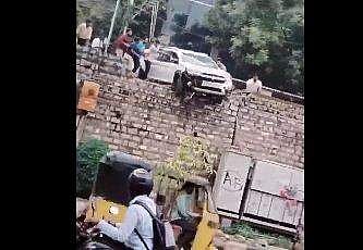 സംരക്ഷണഭിത്തിയില്‍ തൂങ്ങിനില്‍ക്കുന്ന കാറിന്റെ ദൃശ്യം