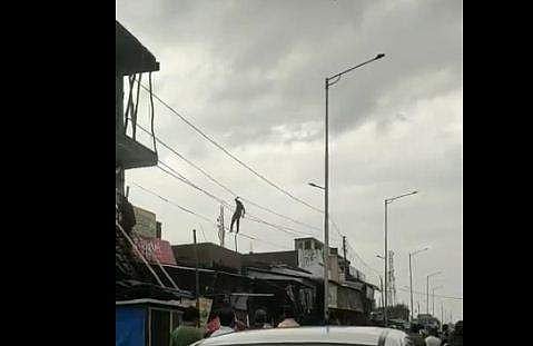 വൈദ്യുതി കമ്പിയില്‍ തൂങ്ങിക്കിടന്ന് യുവാവിന്റെ അഭ്യാസ പ്രകടനം