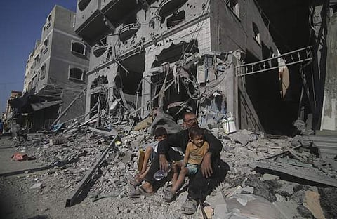ഇസ്രയേൽ ആക്രമണത്തിന് മുന്നിൽ തകർന്ന കെട്ടിടത്തിനു മുന്നിൽ പലസ്തീൻ കുടുംബം/ഫോട്ടോ: പിടിഐ
