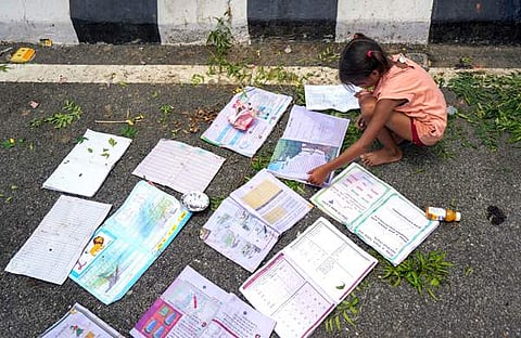 യമുനാ നദിക്ക് ചുറ്റുമുള്ള താഴ്ന്ന പ്രദേശങ്ങളിൽ താമസിക്കുന്നവരെ സുരക്ഷിത സ്ഥാനത്തേക്ക് മാറ്റിപ്പാർപ്പിച്ചപ്പോൾ. നനഞ്ഞ പുസ്തകങ്ങൾ റോഡരികിൽ ഉണക്കാൻ വയ്ക്കുന്ന കുട്ടി/ ചിത്രം: പിടിഐ