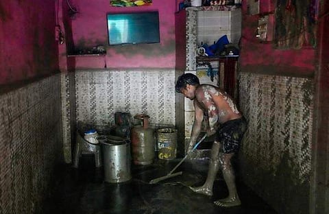 വെള്ളം ഇറങ്ങിയ വീട്ടിൽ നിന്ന് ചെളി നീക്കുന്നു/ ചിത്രം: പിടിഐ