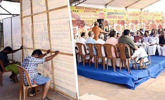 മന്ത്രിയുടെ പ്രസംഗ വേദിയില്‍ ബോര്‍ഡ് താങ്ങാന്‍ തൊഴിലാളികള്‍; വിമര്‍ശനം 
