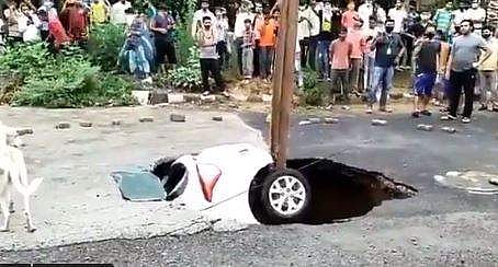 കനത്തമഴയില്‍ റോഡില്‍ അഗാധ ഗര്‍ത്തം, ഓടുന്ന കാര്‍ കുഴിയിലേക്ക്, പൊലീസുകാരന്‍ അത്ഭുതകരമായി രക്ഷപ്പെട്ടു - വീഡിയോ 